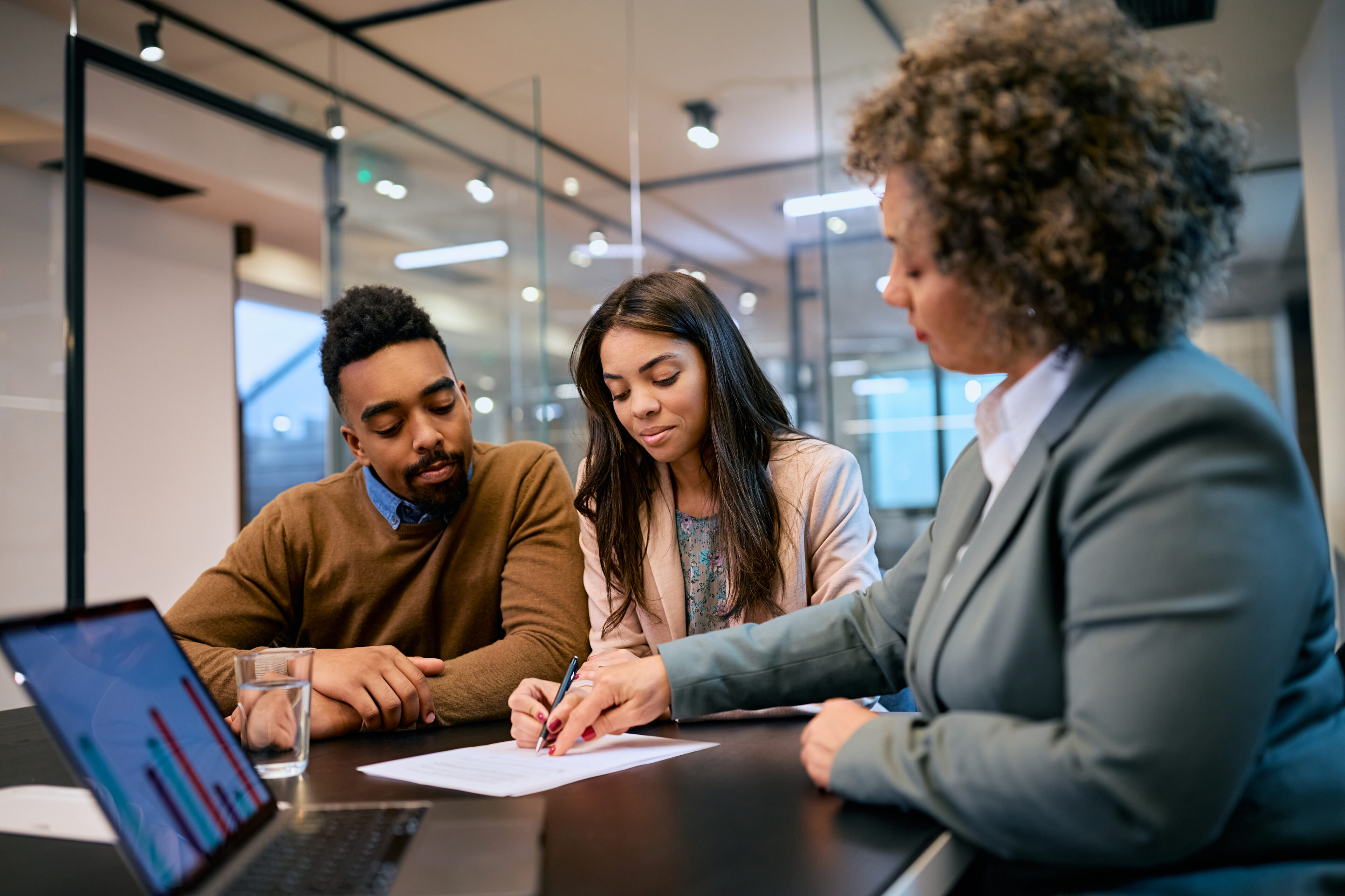 Business meeting with three people discussing documents.
